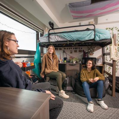 Students sitting and talking in a residence hall room.